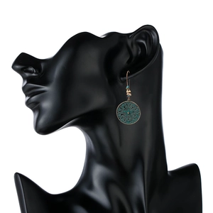 Bohemian vintage hollow mandala drop earrings in bronze and turquoise displayed on model