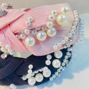 Detailansicht eines Knotenstirnbands mit Perlen und Strass auf plissiertem Stoff