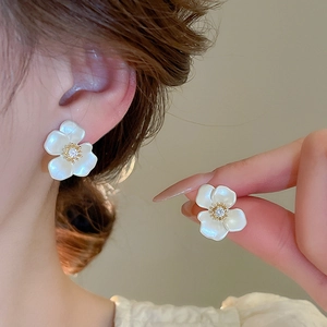 Detailed macro view of gold plated flower stud earrings with zircon center and pearl luster