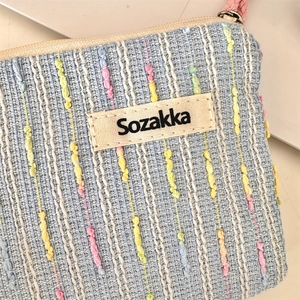 Detailaufnahme der blauen Tweed-Stoffstruktur an einer kleinen Kosmetiktasche