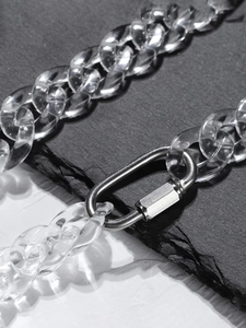 Close-up of a silver metal carabiner clasp on a clear acrylic link chain necklace