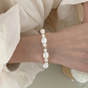 Detail of natural freshwater pearl bracelet with gold beads on model's wrist