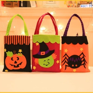 Three Halloween felt gift bags with pumpkin, witch and spider designs by a warm fireplace