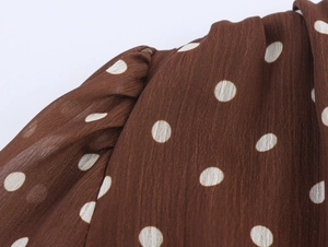 Détail macro du tissu en mousseline marron plissée avec motif à pois blancs