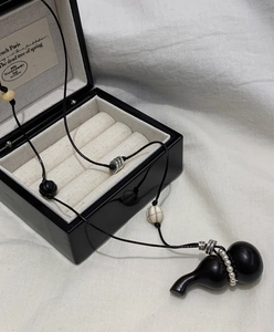 Detail of wooden gourd necklace with pearls inside a luxury black wooden jewelry box