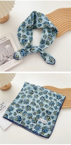 Detail of floral silk scarf in blue and green draped on a wooden tray with fashion book