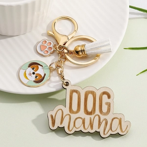Close-up of gold Dog Mama keychain with white tassel and engraved wooden charm