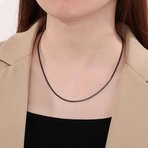 Gros plan d'un collier chaîne gourmette minimaliste en acier noir porté par un mannequin