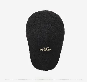 Détail de la casquette baseball en sherpa noir avec broderie PRAIS dorée, vue de haut