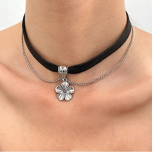 Detail eines doppellagigen Samt-Chokers mit silbernem Blumenanhänger und feiner Metallkette