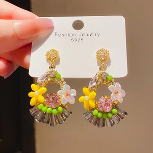 Close-up of vintage drop earrings with colorful resin flowers and gray crystal tassels