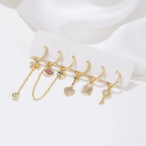 Golden heart earring set with zircon butterfly and key charms on a white background