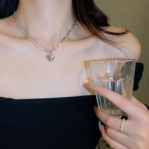 Double-layered silver necklace with crystal heart and star pendant worn by model