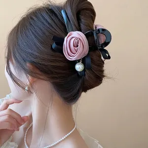 Pink fabric rose hair claw clip with pearl charm shown on model hair for elegant styling