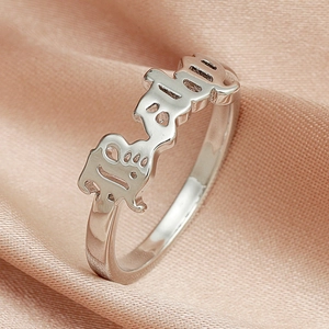 Macro shot of silver ring featuring artistic hollowed-out Baby lettering on smooth silk
