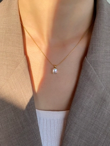 Detailed view of square clear zircon pendant on gold titanium steel necklace on model