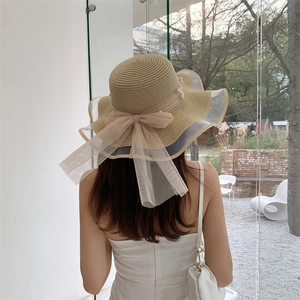 Detail of summer straw hat featuring pink mesh bow and elegant pearl embellishments