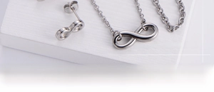 Polished silver infinity symbol necklace and earring set on a white textured board