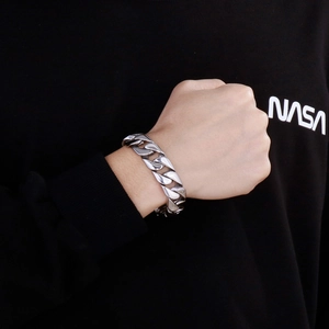 Close-up of a silver Cuban link bracelet made of polished titanium steel on a male wrist