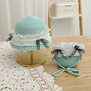 Détail d'un chapeau de paille bleu clair et sac assorti avec dentelle et nœuds noirs