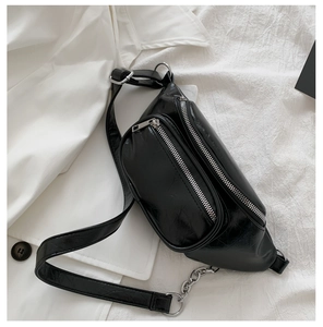 Close-up of black leather chest bag with silver chain and textured wrinkled surface