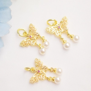 Detailed macro view of 14K gold butterfly pendant with red stone and pearl drops