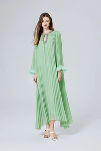 Détail de la robe plissée verte avec poignets en plumes et broderies perlées à l'encolure