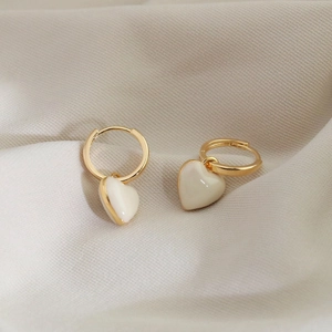 Détail de boucles d'oreilles plaquées or en forme de cœur sur fond de tissu doux
