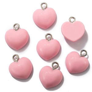 Collection of seven pink resin heart pendants with silver metal rings on white background