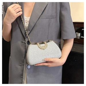 Detail of silver sequin clutch bag with gold round handle and metal chain strap