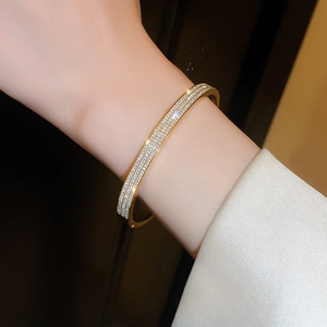 Dettaglio del bracciale placcato oro con zirconi cubici indossato sul polso di una modella
