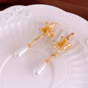 Elegant gold flower pearl earrings with teardrop pearls on a decorative white plate