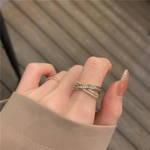 Bague croisée en X dorée luxueuse sertie de zircons étincelants sur la main d'un modèle