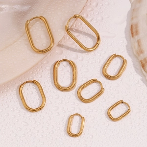 Macro detail of gold-plated U-shaped earrings in multiple sizes on a water-drop surface