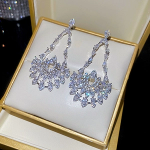 Macro shot of silver drop earrings with marquise-cut zircons in a golden jewelry box