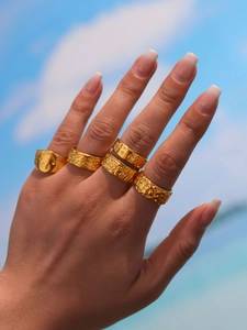 Golden rings set on hand with beach background showing smiley and Celtic knot details