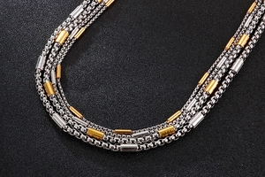 Macro detail of multi-layered stainless steel box chain necklace with gold and silver beads