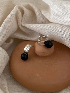 Detailed shot of 925 sterling silver hoop earrings with faceted black beads on ceramic