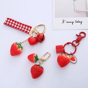 Detailed macro view of cute red strawberry keychains with golden heart and bell charms
