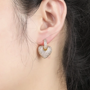 Close-up of heart-shaped gold earrings with micro-paved zircons worn on model ear
