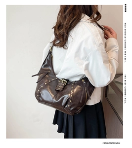Detail der dunkelbraunen Leder-Schultertasche mit Vintage-Nieten und Metallschnallen-Gurt