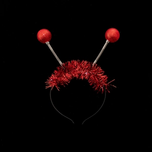 Detail of red alien headband with spring-loaded glitter balls and festive tinsel fringe