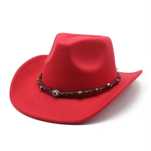Dettaglio di cappello da cowboy in feltro rosso con fascia intrecciata e amuleto