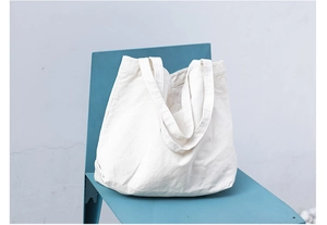 Close-up of minimalist cream white canvas tote bag placed on a blue designer chair