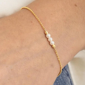 Detail of s925 silver gold bracelet featuring three elegant white pearls worn on wrist