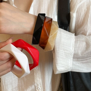 Stack of chunky geometric resin bangles in amber, marble, black, red, and white