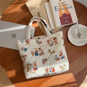 Detailed view of a white quilted cotton tote bag featuring cute cartoon rabbit prints