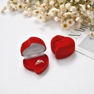 Macro shot of red heart-shaped velvet ring box with rose relief and diamond ring inside