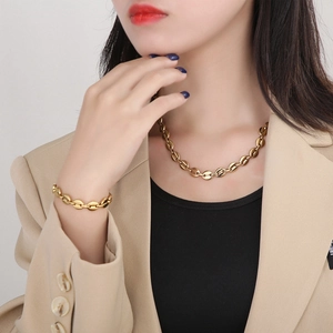 Close-up of golden coffee bean link necklace and bracelet set worn by a fashion model