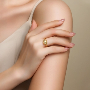 Detailed view of a gold minimalist bean ring with a single moissanite on a model's hand